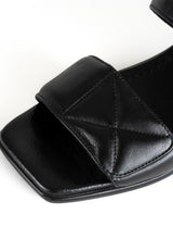 Load image into Gallery viewer, Detailfoto einer minimalistischen Sandale in schwarzem Glattleder mit Karree Leisten und zwei gepolsterten Riemen mit dekorativen Nähten im Quilted-Look