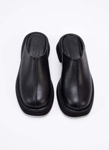 Load image into Gallery viewer, Draufsicht auf ein Paar Clogs aus hochwertigem, schwarzem Leder mit dezentem Finish. Ein tolles Detail ist die erhobene Mittelnaht, die dem ansonsten puristischen Modell einen spannenden Touch verleiht. Die Schuhe sind optisch und von der Wertigkeit mit The Row vergleichbar, bieten jedoch einen erschwinglichen Preis. Cedoublé bietet klassische Ware mit besonderen Details, die keinen Trends nacheifern, sondern viele Jahre tragbar sind. Diese Clogs können mit schwarzer Schuhcreme ganz einfach gepflegt werden.