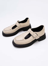 Load image into Gallery viewer, Abbildung von Mary Jane Schuhen mit dezenter Plaetausohle und modelltypischem T-Strap. Das Echtleder ist in einem sanften Beigeton gehalten, alle Kontraste wie die Laufsohle, das Lederfutter und die dekorative Naht auf der Front sind schwarz.