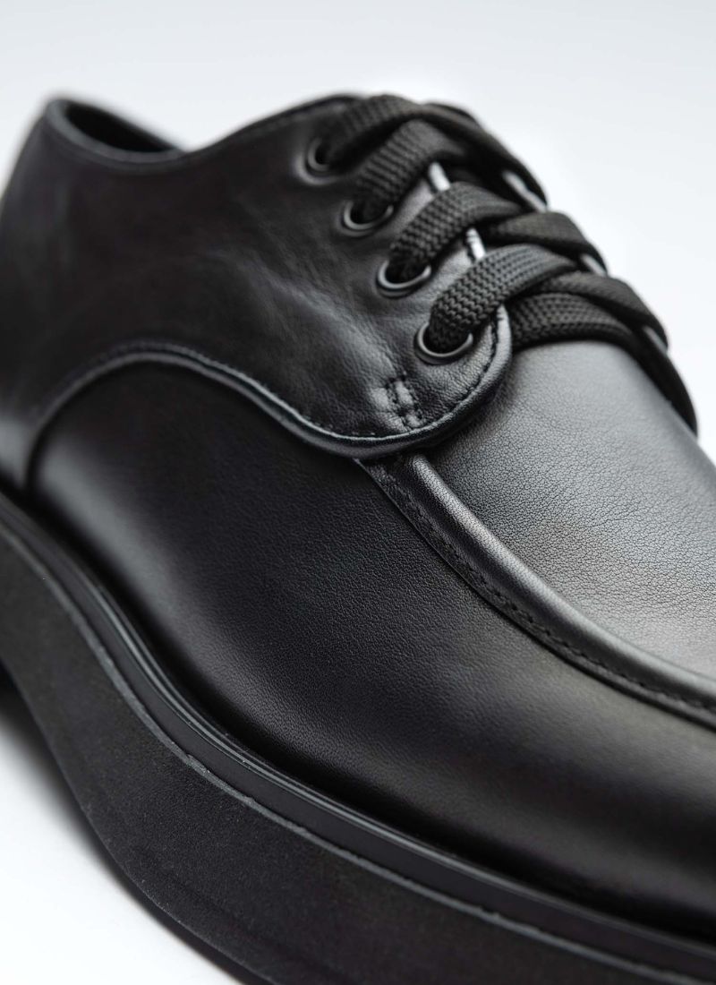 Schuhfront eines schwarzen Lederhalbschuhs des Labels Cedoublé. Zu erkennen sind der feine Glanz des zertifizierten Leders, die Wulstnaht auf der Front sowie ein Teil der Laufsohle und die schwarzen Schnürsenkel.