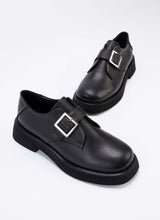 Lade das Bild in den Galerie-Viewer, Ein Paar luxuriöse Halbschuhe aus hochwertigem, schwarzem Leder mit Lederriemen über dem Spann und silberfarbener, eckiger Schnalle. Auch die Sohle und das Futter sind passend schwarz. Die Schuhe sind vom Hersteller Cedoublé und werden unter fairen Bedingungen in Europa produziert.