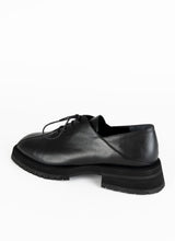 Load image into Gallery viewer, Produktfoto eines burschikosen Unisex-Schnürschuhs aus Leder mit Oxford-Schnürung und ausgeprägter Laufsohle in schwarz. Eine asymmetrische Naht ziert die Schuhfront