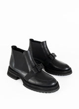 Load image into Gallery viewer, Ein Paar schwarze Chelseaboots aus Leder mit weitflächigem Elastikeinsatz und dekorativer Schnalle in Schleifenoptik. Dieses Schleifendetail schmiegt sich über den Spann.