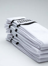 Load image into Gallery viewer, Aufeinander gestapelte Tennissocken des Labels Cedoublé in weiß-schwarz mit Logo. Es handelt sich um ein Produktbild. Auf dem Foto gut ersichtlich ist die Qualität aus Bio-Baumwolle. Die Strümpfe sind unisex tragbar.