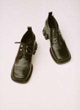 Load image into Gallery viewer, Analoges Foto von einem Paar extravaganter, schwarzer Lederschuhe mit Schnürung, Ösen und einem besonderen, klobigen Absatz. Die Schuhfront hat eine Karreeform.