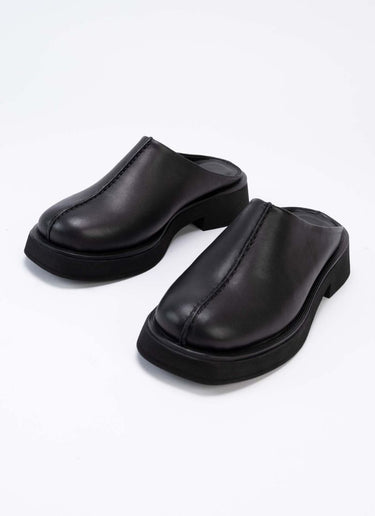 Exklusive Leder-Clogs mit geschlossener Front und offener Hinterkappe aus schwarzem Leder. Optisches Highlight ist die prägnante Mittelnaht, die vertikal über den Schaft verläuft. Die Mules sind hautfreundlich mit schwarzem Leder gefüttert und sorgen so allzeit für ein frisches Fußklima. Die Laufsohle ist leicht erhöht und ebenfalls schwarz.