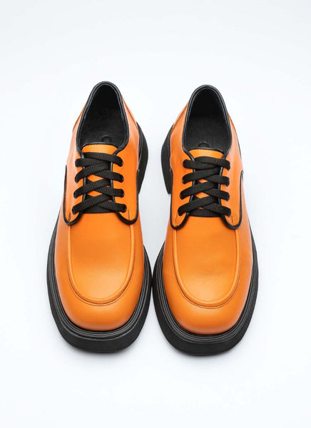 Ein Paar knallig orangefarbene unisex Lederschuhe zum Schnüren mit Wulstnaht