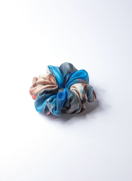Elastisches Haargummi aus 100% upcycled Seide, welche von einem hochwertigen Seidentuch im Batiklook stammt. Das Scrunchie weist einen Farbverlauf auf, bei den Tönen handelt es sich um türkisblau, sandfarben und terracotta.